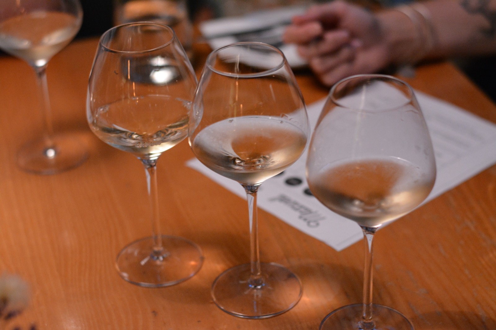 Three tasting pours side by side on a wood table at a Grown Up Bar Crawl stop